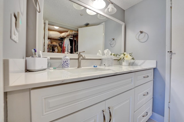 15355 Lakes Of Delray Blvd Unit 211, Delray Beach, FL 33484 - bathroom featuring a textured ceiling, vanity, and a spacious closet