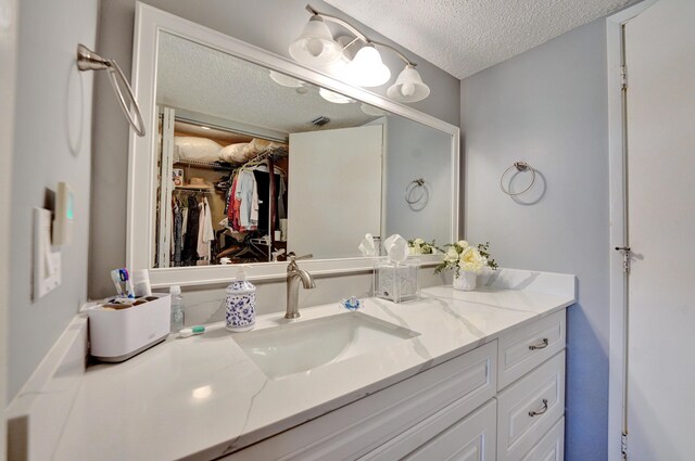 15355 Lakes Of Delray Blvd Unit 211, Delray Beach, FL 33484 - bathroom featuring a textured ceiling, vanity, and a walk in closet