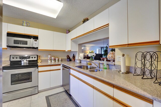 15355 Lakes Of Delray Blvd Unit 211, Delray Beach, FL 33484 - kitchen with appliances with stainless steel finishes, a sink, white cabinets, a textured ceiling, and light tile patterned floors