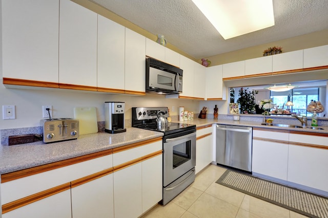 15355 Lakes Of Delray Blvd Unit 211, Delray Beach, FL 33484 - kitchen featuring appliances with stainless steel finishes, a sink, light countertops, light tile patterned flooring, and a textured ceiling