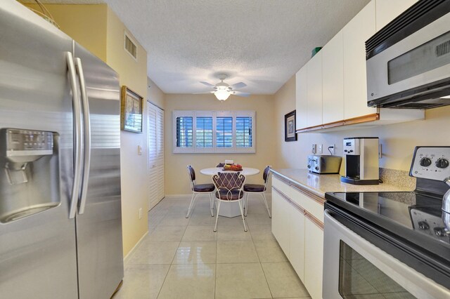 15355 Lakes Of Delray Blvd Unit 211, Delray Beach, FL 33484 - kitchen featuring stainless steel appliances, white cabinets, light countertops, ceiling fan, and a textured ceiling
