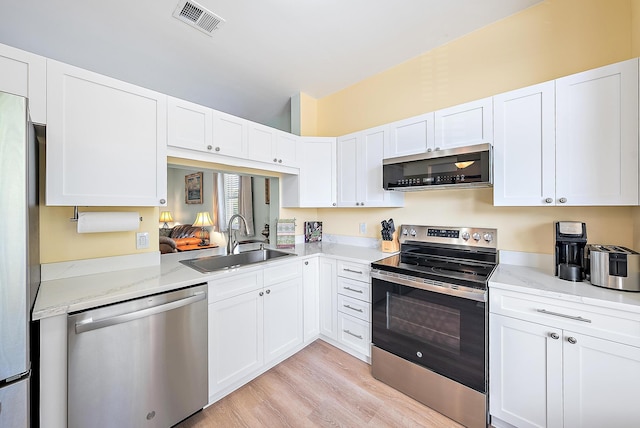 18081 SE Country Club Dr Unit 370, Tequesta, FL 33469 - kitchen with stainless steel appliances, a sink, light wood-type flooring, and white cabinets