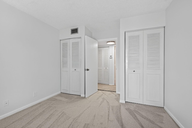 1104 Green Pine Blvd Unit D2, West Palm Beach, FL 33409 - unfurnished bedroom with multiple closets, carpet floors, and a textured ceiling