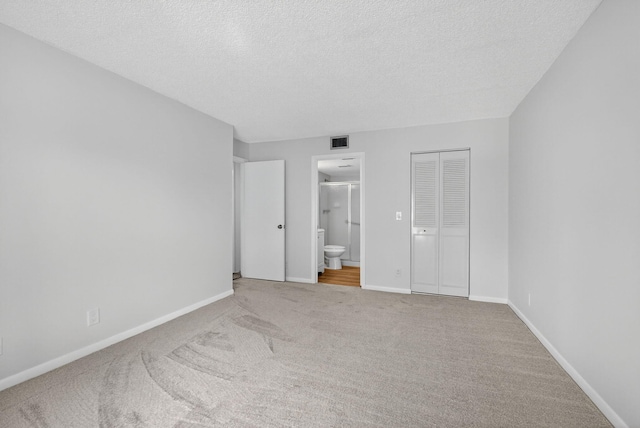 1104 Green Pine Blvd Unit D2, West Palm Beach, FL 33409 - unfurnished bedroom featuring carpet, connected bathroom, and a textured ceiling