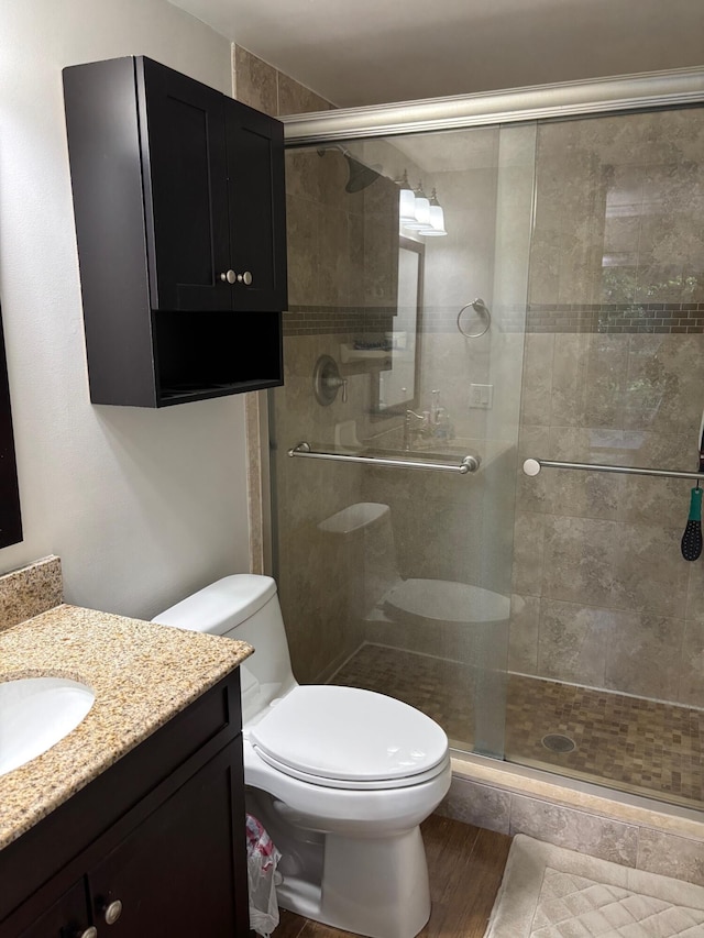 full bathroom featuring a shower stall, toilet, vanity, and wood finished floors