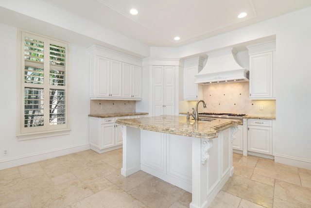 3309 S Flagler Dr, West Palm Beach, FL 33405 - kitchen featuring premium range hood, light stone countertops, a sink, white cabinetry, and recessed lighting