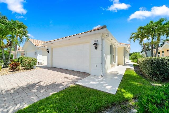 1056 SW Balmoral Trce, Stuart, FL 34997 - view of side of home with a tiled roof, stucco siding, a garage, and decorative driveway