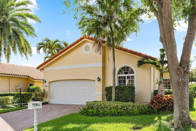 5350 Casa Real Dr, Delray Beach, FL 33484 - mediterranean / spanish house with stucco siding, an attached garage, decorative driveway, and a tiled roof