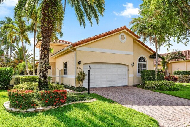 5350 Casa Real Dr, Delray Beach, FL 33484 - mediterranean / spanish house featuring an attached garage, decorative driveway, stucco siding, a tiled roof, and a front yard
