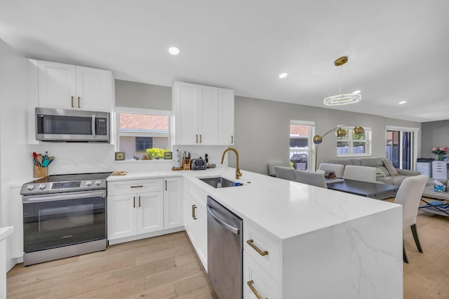 8076 Sweetbriar Way, Boca Raton, FL 33496 - kitchen with stainless steel appliances, a sink, a peninsula, white cabinets, and light wood-style floors
