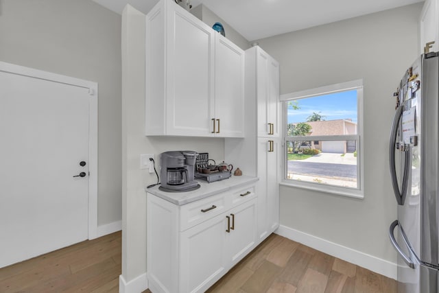 8076 Sweetbriar Way, Boca Raton, FL 33496 - kitchen with freestanding refrigerator, light wood-style flooring, white cabinetry, and baseboards