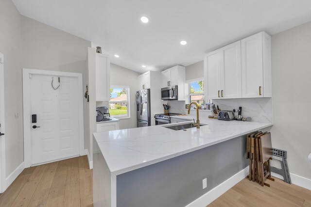 8076 Sweetbriar Way, Boca Raton, FL 33496 - kitchen with appliances with stainless steel finishes, a sink, light wood finished floors, light stone countertops, and a peninsula