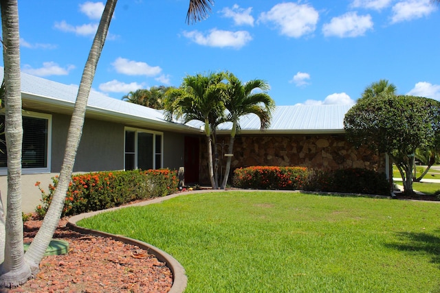 2182 SE Bersell Rd, Port Saint Lucie, FL 34952 - view of front of house with a front lawn, stucco siding, metal roof, and stone siding