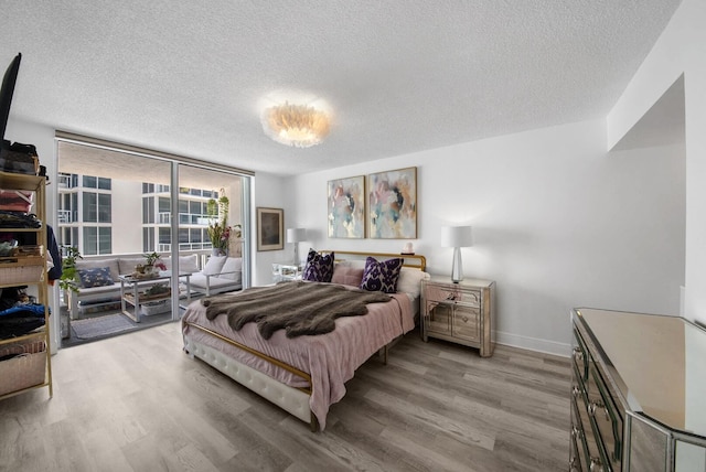 3570 S Ocean Blvd Unit 506, South Palm Beach, FL 33480 - bedroom with light wood-style flooring, a wall of windows, a textured ceiling, baseboards, and access to exterior