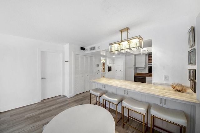 3570 S Ocean Blvd Unit 506, South Palm Beach, FL 33480 - kitchen featuring dishwasher, a breakfast bar, a peninsula, wood finished floors, and light countertops