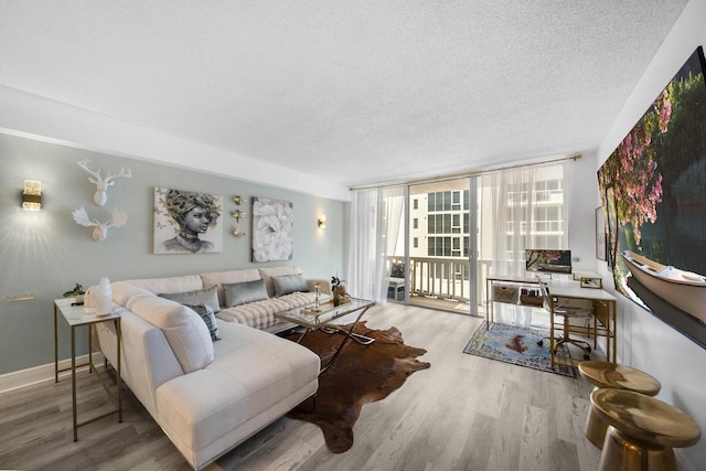 3570 S Ocean Blvd Unit 506, South Palm Beach, FL 33480 - living room featuring a textured ceiling, wood finished floors, a wall of windows, and baseboards