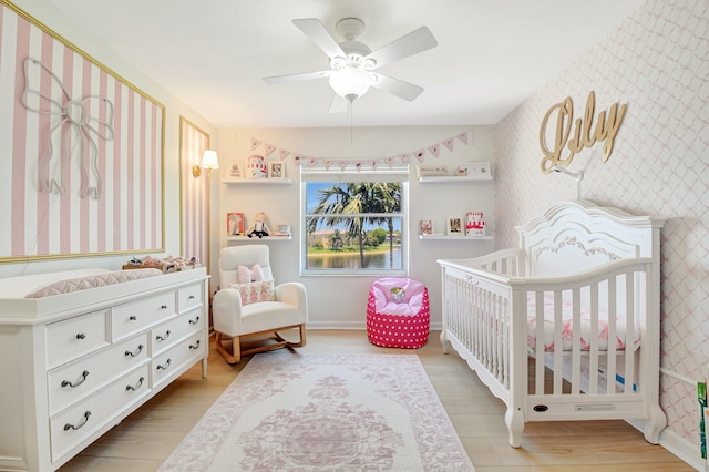 9800 Stover Way, Wellington, FL 33414 - bedroom featuring wallpapered walls, a nursery area, wood finished floors, and a ceiling fan