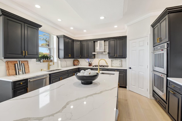 9800 Stover Way, Wellington, FL 33414 - kitchen featuring wall chimney range hood, stainless steel appliances, a sink, light wood-style floors, and light stone counters