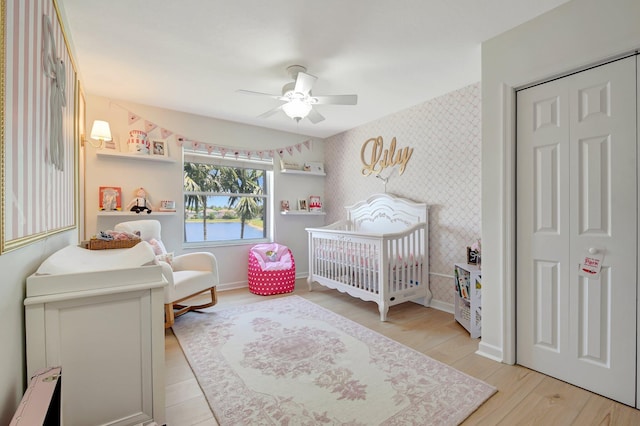 9800 Stover Way, Wellington, FL 33414 - bedroom featuring wallpapered walls, a crib, light wood-type flooring, a ceiling fan, and baseboards