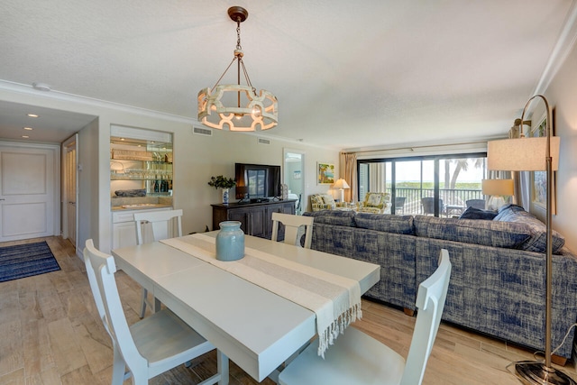 2641 NE Ocean Blvd Unit 106, Stuart, FL 34996 - dining room with a chandelier, light wood-style flooring, and crown molding