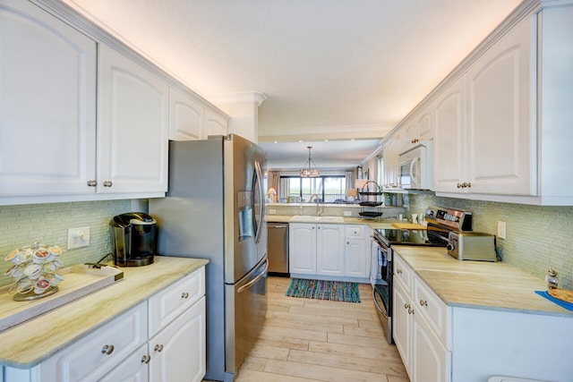 2641 NE Ocean Blvd Unit 106, Stuart, FL 34996 - kitchen featuring appliances with stainless steel finishes, backsplash, light wood-type flooring, and white cabinetry