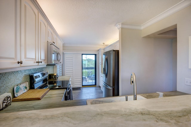 2641 NE Ocean Blvd Unit 106, Stuart, FL 34996 - kitchen featuring stainless steel appliances, ornamental molding, a textured ceiling, wood finished floors, and light stone countertops