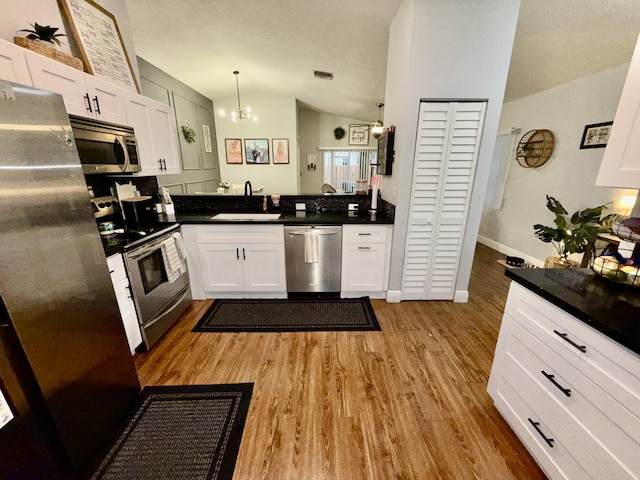 8421 SW 41st Ct, Davie, FL 33328 - kitchen with stainless steel appliances, a sink, vaulted ceiling, light wood-style flooring, and white cabinetry