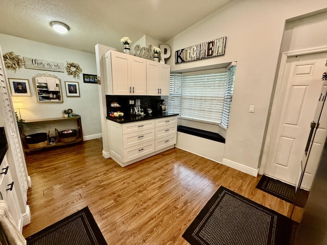 8421 SW 41st Ct, Davie, FL 33328 - kitchen with white cabinetry, baseboards, light wood finished floors, dark countertops, and vaulted ceiling