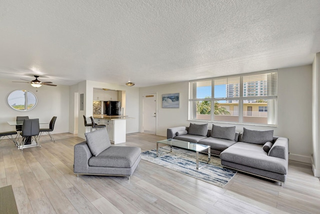3640 N Ocean Dr Unit 427, Singer Island, FL 33404 - living room featuring a textured ceiling, light wood-style floors, a ceiling fan, and baseboards