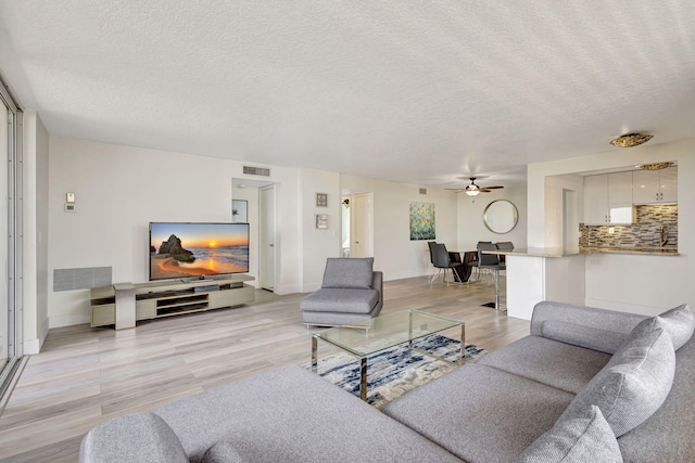 3640 N Ocean Dr Unit 427, Singer Island, FL 33404 - living area featuring a textured ceiling, light wood finished floors, ceiling fan, and baseboards