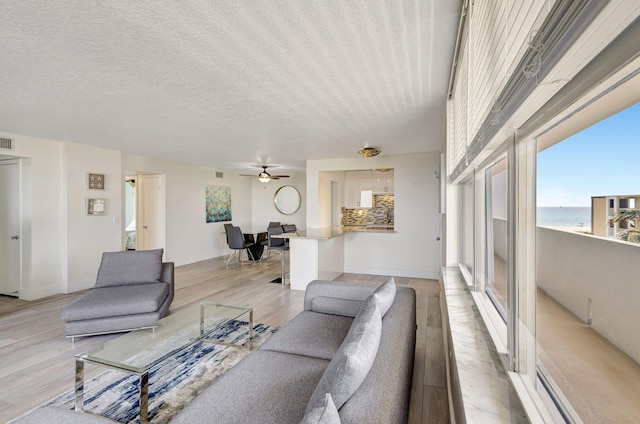 3640 N Ocean Dr Unit 427, Singer Island, FL 33404 - living room with light wood-style flooring, a ceiling fan, baseboards, a water view, and a textured ceiling