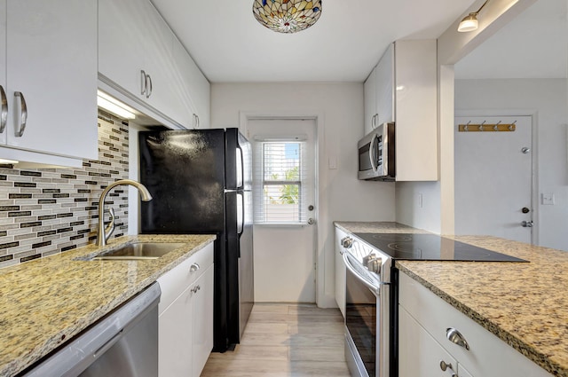 3640 N Ocean Dr Unit 427, Singer Island, FL 33404 - kitchen with appliances with stainless steel finishes, a sink, light wood-style flooring, tasteful backsplash, and white cabinets