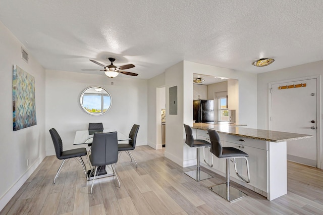3640 N Ocean Dr Unit 427, Singer Island, FL 33404 - dining room featuring electric panel, light wood-type flooring, a ceiling fan, a textured ceiling, and baseboards
