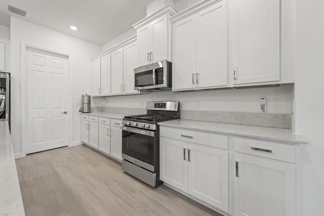 19404 Broad Shore Walk, Loxahatchee, FL 33470 - kitchen with appliances with stainless steel finishes, white cabinets, recessed lighting, light wood finished floors, and light stone countertops
