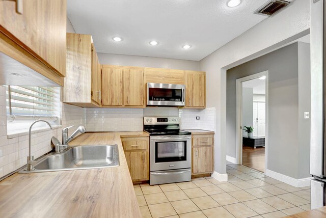 9062 NW 20th Mnr, Coral Springs, FL 33071 - kitchen featuring appliances with stainless steel finishes, a sink, light brown cabinets, decorative backsplash, and light tile patterned floors