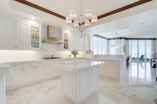 5050 N Ocean Dr Unit 1701, Singer Island, FL 33404 - kitchen with wall chimney range hood, a chandelier, ornamental molding, light marble finish floors, and a peninsula