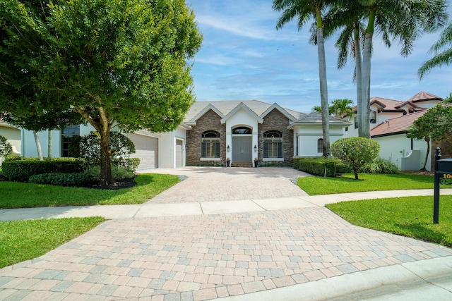 10652 Versailles Blvd, Wellington, FL 33449 - view of front of home featuring decorative driveway, a front lawn, stucco siding, and stone siding