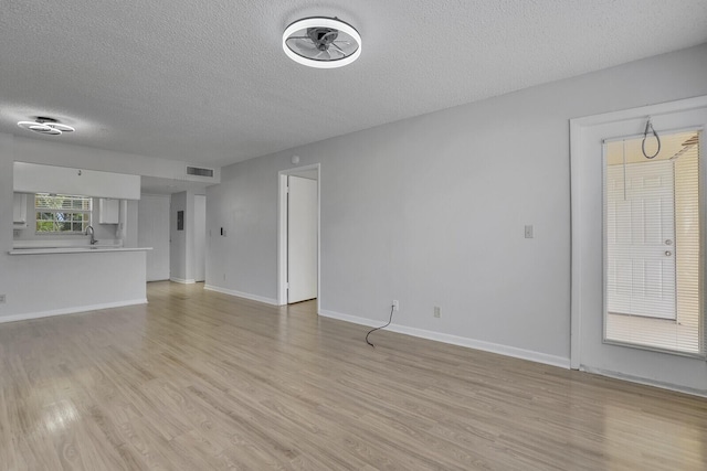 6315 La Costa Dr Unit G, Boca Raton, FL 33433 - unfurnished living room with a textured ceiling, light wood-style floors, and baseboards