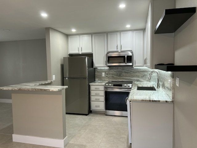 267 Flanders F, Delray Beach, FL 33484 - kitchen featuring appliances with stainless steel finishes, light tile patterned flooring, light stone countertops, recessed lighting, and white cabinets