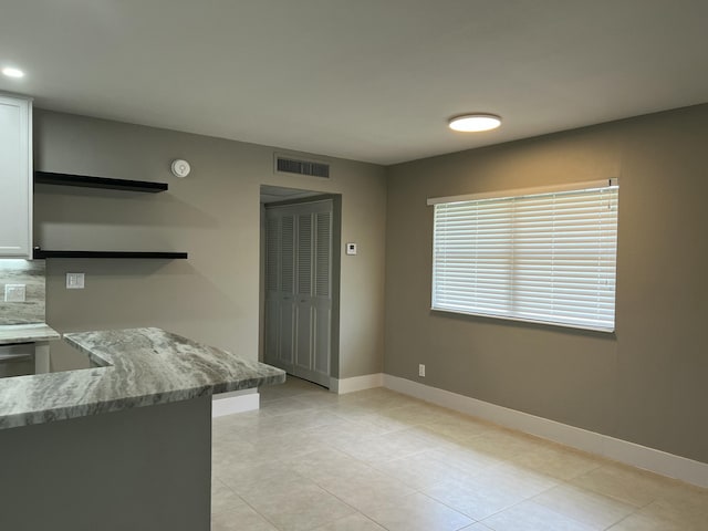 267 Flanders F, Delray Beach, FL 33484 - kitchen featuring open shelves, light tile patterned floors, white cabinets, decorative backsplash, and light stone counters