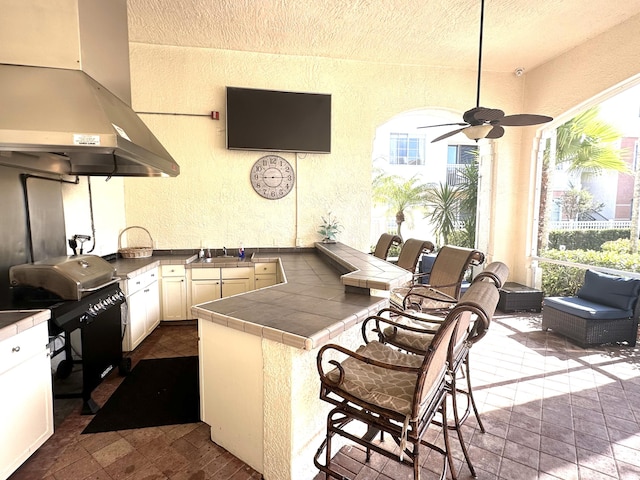 5205 Myrtlewood Cir E, Palm Beach Gardens, FL 33418 - kitchen featuring tile countertops, range hood, a textured wall, healthy amount of natural light, and a peninsula