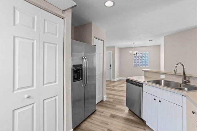 1413 Amaryllis Ln, West Palm Beach, FL 33415 - kitchen with appliances with stainless steel finishes, a sink, a chandelier, light wood-style floors, and light countertops