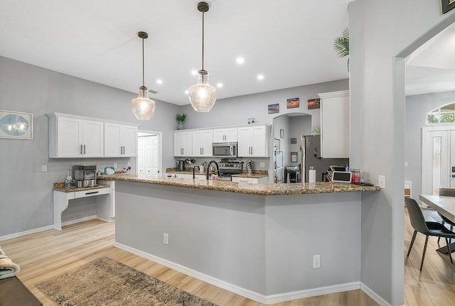 1025 Whitetail Ave SW, Vero Beach, FL 32968 - kitchen with appliances with stainless steel finishes, light stone counters, light wood-type flooring, a peninsula, and recessed lighting