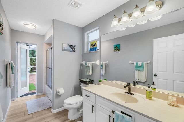 1025 Whitetail Ave SW, Vero Beach, FL 32968 - full bathroom with toilet, baseboards, wood finished floors, vanity, and bath / shower combo with glass door