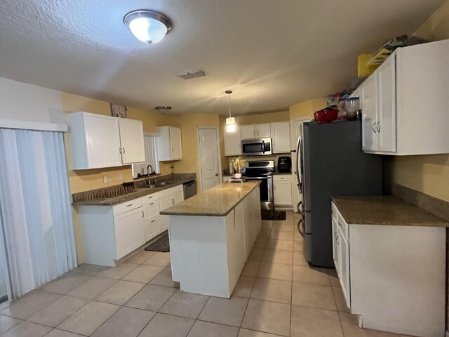 991 SE Bywood Ave, Port Saint Lucie, FL 34983 - kitchen with appliances with stainless steel finishes, a center island, white cabinets, light tile patterned flooring, and a sink