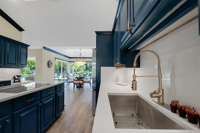 4164 Saint Andrews Dr, Boynton Beach, FL 33436 - kitchen with black electric cooktop, ornamental molding, blue cabinetry, light countertops, and light wood-style flooring