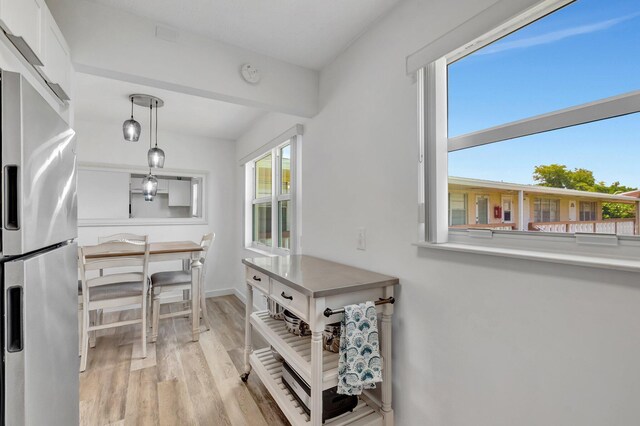 229 Chatham K, West Palm Beach, FL 33417 - kitchen with freestanding refrigerator, light wood-style flooring, decorative light fixtures, baseboards, and white cabinets