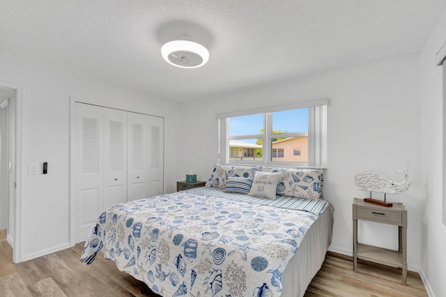 229 Chatham K, West Palm Beach, FL 33417 - bedroom with light wood-style floors, a closet, baseboards, and a textured ceiling