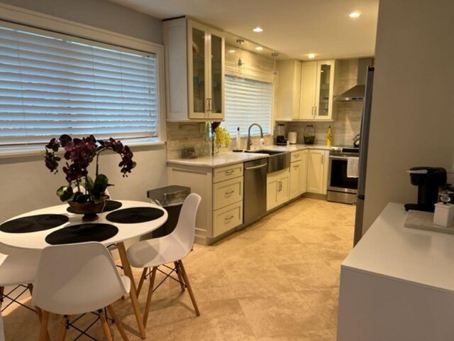501 SE 13th Ct, Pompano Beach, FL 33060 - kitchen with stainless steel appliances, backsplash, light countertops, glass insert cabinets, and white cabinetry