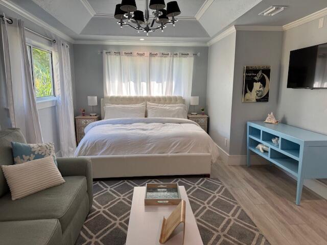 501 SE 13th Ct, Pompano Beach, FL 33060 - bedroom with a raised ceiling, wood finished floors, a chandelier, ornamental molding, and baseboards